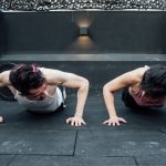Two adults doing push-ups in an indoor gym setting in Mexico City, promoting a fit and healthy lifestyle.